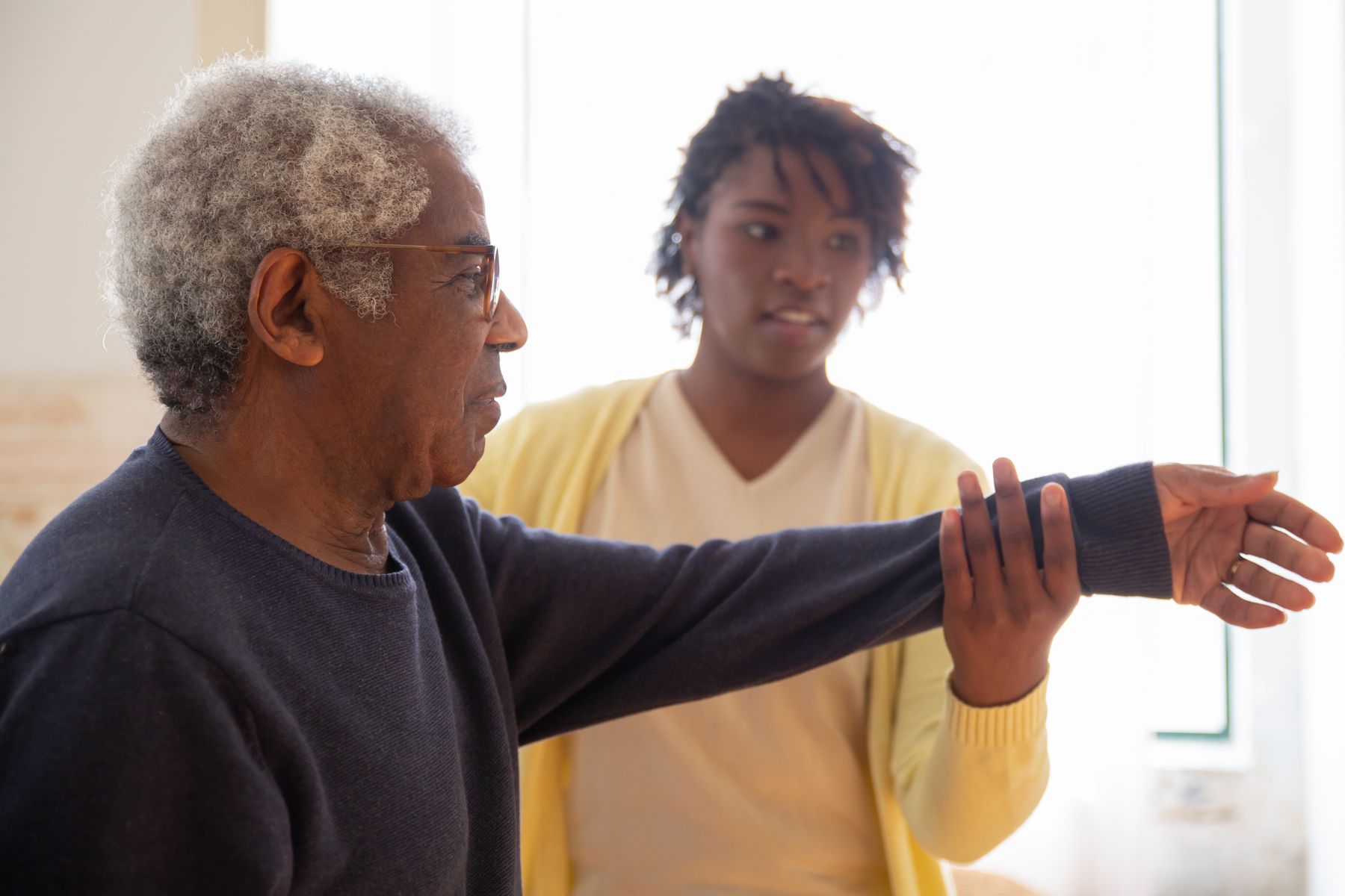 Therapist guiding an older man through an arm exercise